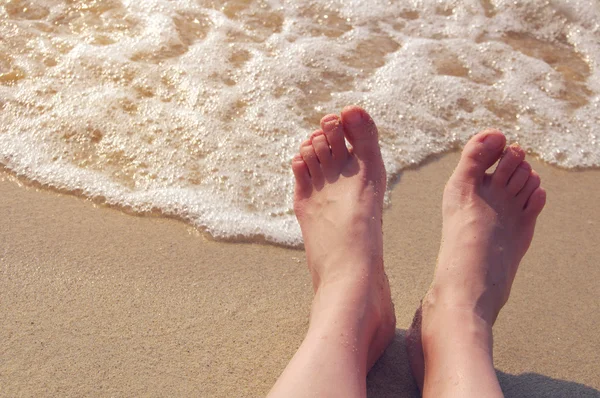 Pies femeninos en una playa contra el mar en un día soleado de verano . —  Fotos de Stock