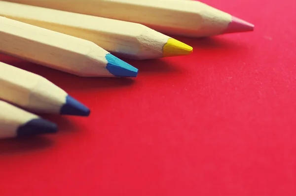 Кольорові дерев'яні олівці на червоному тлі — стокове фото
