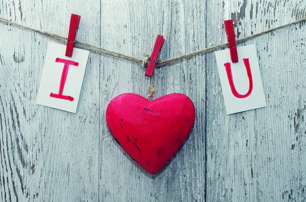 Red heart and card text I LOVE YOU holds on  on wooden cloth pegs on a rope on old wooden background. — Stok fotoğraf