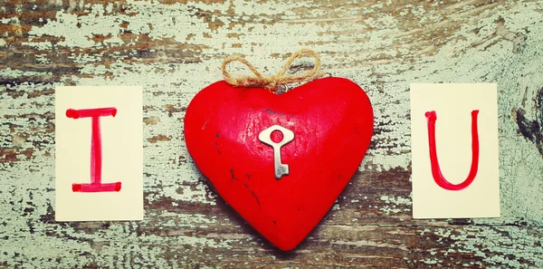 Red heart with a small metal key and card text I LOVE YOU on old wooden background. — Stok fotoğraf