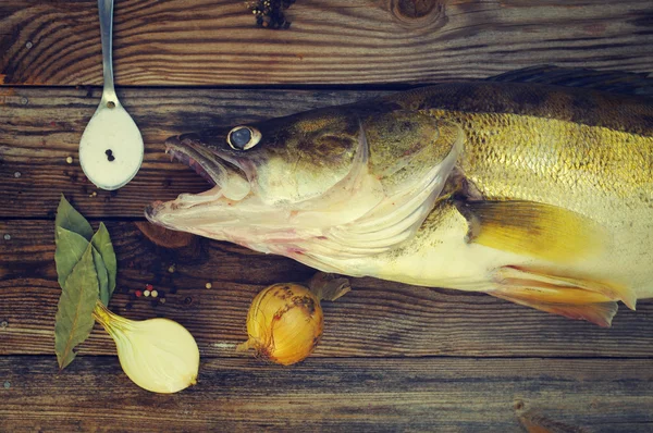 Fisk en flod gös på en planka med salt, lagerblad, lök, paprika. — Stockfoto