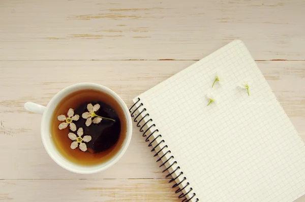 Cup of tea with spring flowers and notebook