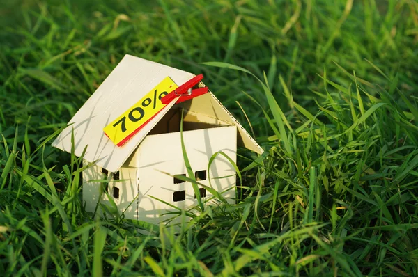House from paper with an empty yellow card with an inscription of 70% in a green grass. — Stock Photo, Image