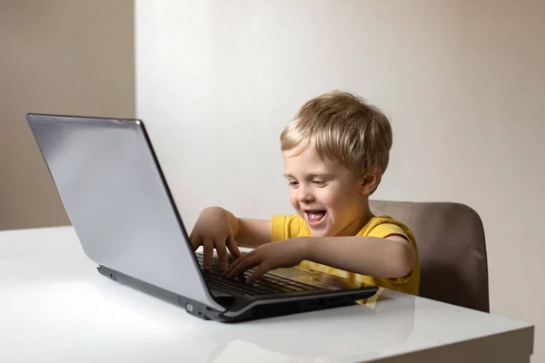 Menino Bonito Com Cabelo Loiro Senta Uma Mesa Com Laptop — Fotografia de Stock