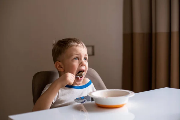 Niño Lindo Con Pelo Rubio Come Gachas Con Una Cuchara — Foto de Stock