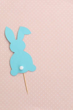 Pembe arka planda mavi renkli Paskalya tavşanı. Çubukta at kuyruklu Paskalya tavşanı. Paskalya dekoru. Paskalya ve yaratıcı konsept.