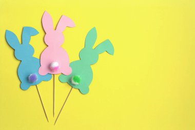 Sarı arka planda renkli Paskalya tavşanları. Kabarık kuyruklu Paskalya tavşanları. Paskalya dekoru. Paskalya ve yaratıcı konsept.