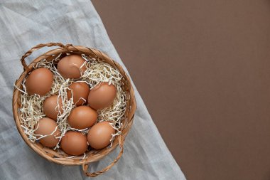 Doğal sağlıklı beslenme ve organik gıda konsepti. Sepette çiğ tavuk yumurtası. Üst görünüm ve kahverengi arkaplan.