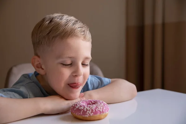 Koncept Neužitečné Jídlo Malý Kluk Blond Vlasy Doma Růžovou Koblihu — Stock fotografie