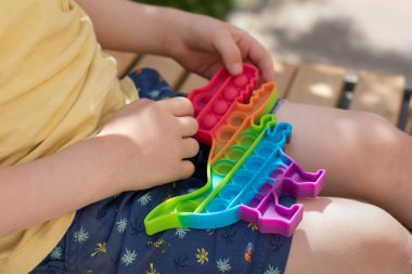 Duygusal denge kavramı. Küçük bir çocuk stres önleyici bir oyuncakla oynuyor. Çok renkli duyusal antidepresan oyuncak dinozor şekline sokuyor..