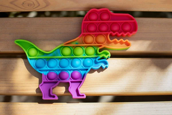 Emotional balance concept. Multicolored sensory silicone antistress toy pop it in the shape of a dinosaur