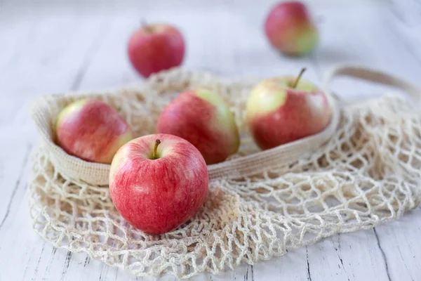 Maturare Deliziose Mele Rosse Una Borsa Rete Uno Sfondo Legno — Foto Stock