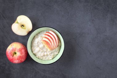 Düzgün beslenme, yemek pişirme kavramı. Bir kase yulaf ezmesi ve koyu arkaplanda sulu kırmızı elmalar. Üst görünüm.