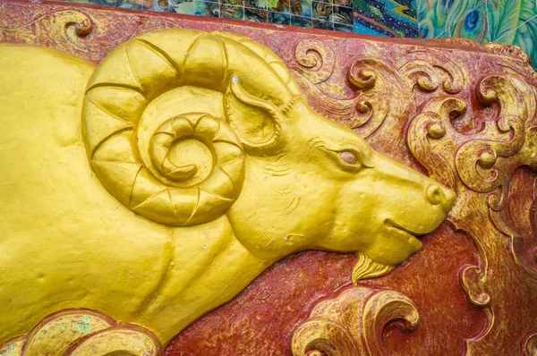 Escultura de cabra dorada en la pared del santuario Imágenes De Stock Sin Royalties Gratis