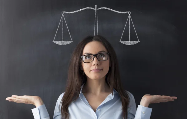 Geschäftsfrau steht mit Gewichtswaage gegen Tafel. — Stockfoto