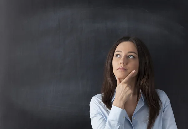 Jeune femme réfléchie sur fond de tableau — Photo