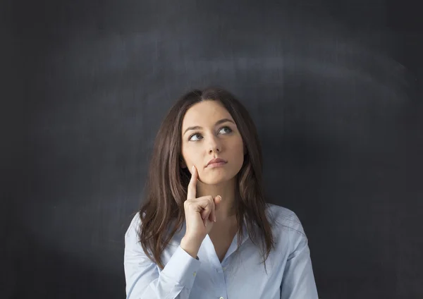 Denken zakenvrouw staat op schoolbord achtergrond. — Stockfoto