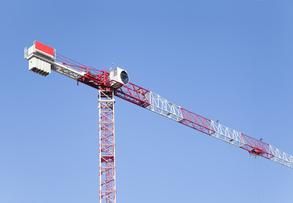 Red construction crane on blue sky