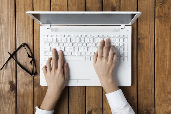 Mujer de negocios utilizando el ordenador portátil y en su mesa de oficina —  Fotos de Stock