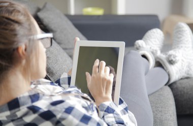 Kadın kanepe oturma odasında yatan ve tablet PC'yi kullanma.