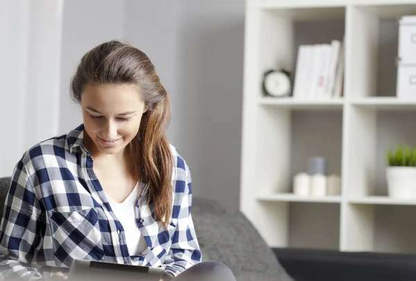 Junge Frau liest auf dem Sofa ein digitales Tablet — Stockfoto