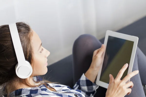 Kvinna med hörlurar lyssnar musik på TabletPC — Stockfoto