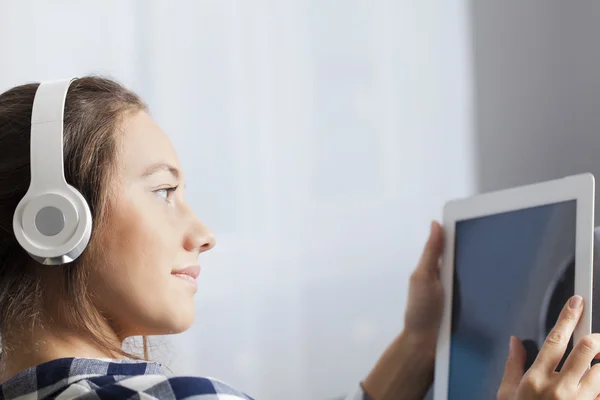 Kvinna med hörlurar lyssnar musik på TabletPC — Stockfoto