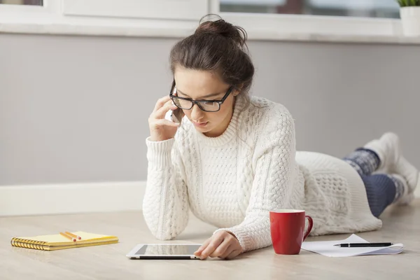 Kvinna med hjälp av Tablet PC-datorn medan du sitter på golvet hemma. — Stockfoto