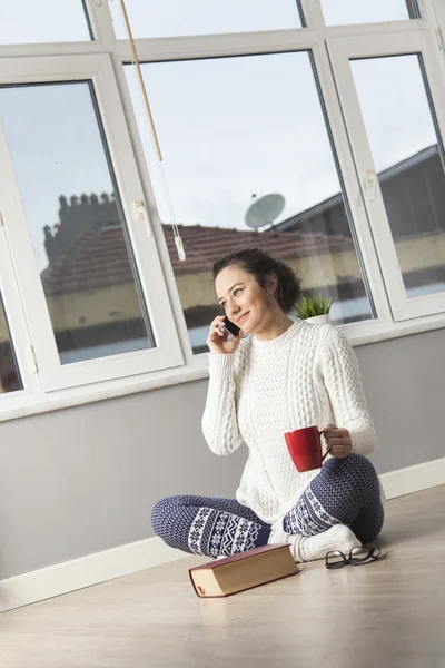 Молодая женщина разговаривает по телефону за чашечкой кофе — стоковое фото
