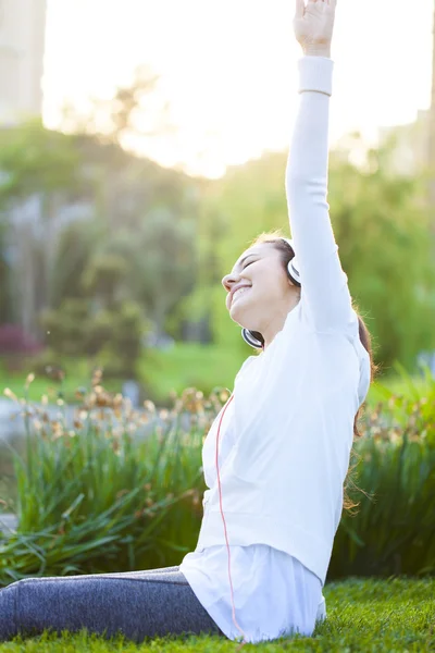 Mujer joven deportiva escuchando música mientras se estira . —  Fotos de Stock