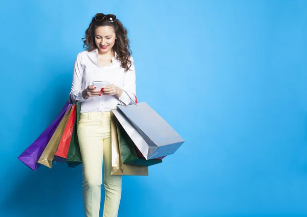 Chica con bolsas de compras sobre fondo azul . —  Fotos de Stock