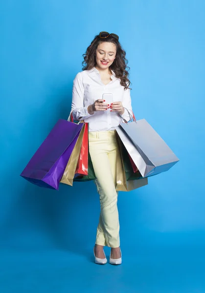 Chica con bolsas de compras sobre fondo azul . — Foto de Stock