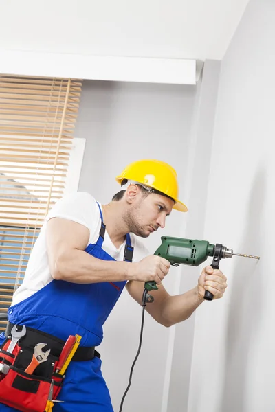 Young man drilling hole in wall — Stock Photo, Image