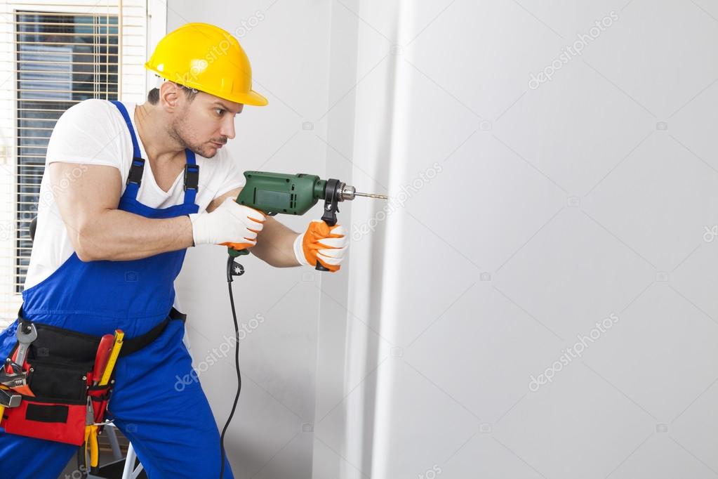 Young man drilling hole in wall Stock Photo by ©dragonstock 120646954