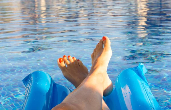 女人的脚靠在游泳池的蓝色水边 — 图库照片
