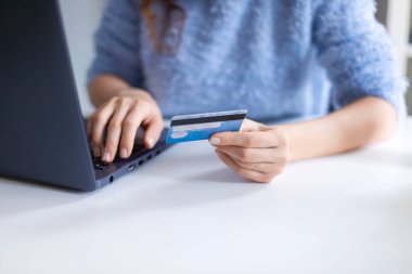 Kadın kredi kartı bilgilerini dizüstü bilgisayar klavyesiyle giriyor. Çevrimiçi alışveriş danışmanları