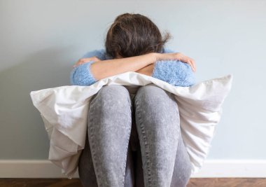 Genç bir kadın oturmuş yerde dizlerine sarılıyor. Üzgün hissediyorum, yatak odasında hayal kırıklığına uğradım.