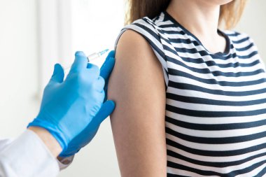 Genç bir kadın bir doktorun ofisinde aşı oluyor.