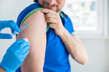 Genç adam bir doktorun ofisinde aşı oluyor.