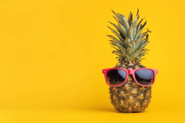 Sarı arka planda güneş gözlüklü ananas, yaz tatili konsepti.
