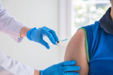 Genç adam bir doktorun ofisinde aşı oluyor.