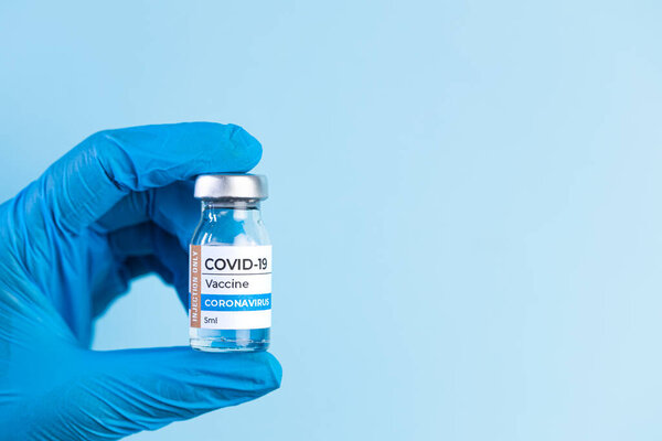 Врач в защитной перчатке держит стеклянную бутылку коронавируса Ковид-19. Коронавирус-2019-nCoV