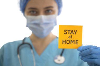 Yüzünde maske olan genç bir doktor ve elinde 