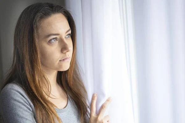 Pensive Tânără Femeie Uită Printr Fereastră — Fotografie, imagine de stoc