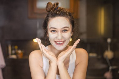 Evde yüz maskesi takan genç bir kadın.