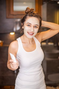 Evde yüz maskesi takan genç bir kadın.