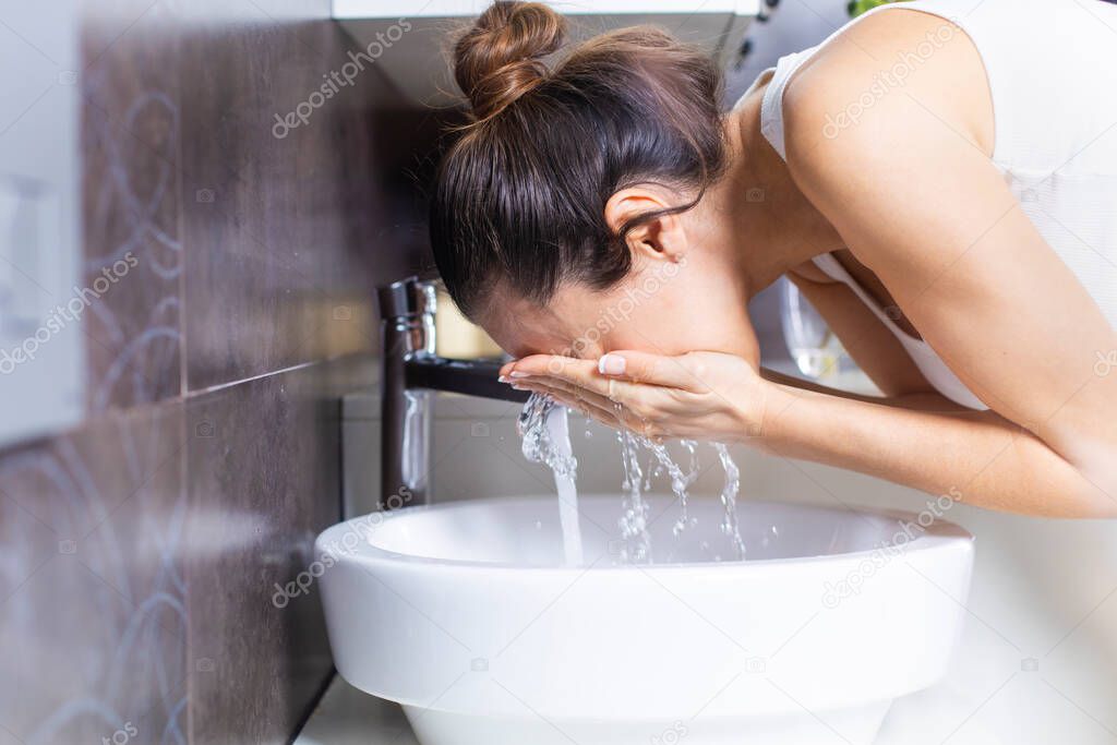Shot of an attractive young woman washing her face in the bathroo