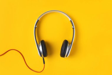 Sarı arkaplanda beyaz kulaklıklar var.