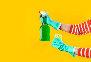 Yeşil eldivenli, paçavra ve sprey deterjan tutan kadın elleri. Ev temizliği konsepti. Temizlik hizmetleri. 