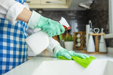 Mutfak tezgahını bez ve sprey temizleyiciyle temizleyen tanınmayan bir kadın.